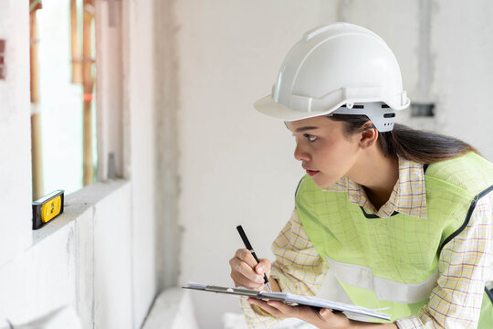 Female worker occupation. Woman inspector / architect checking interior material process in house reconstruction project.