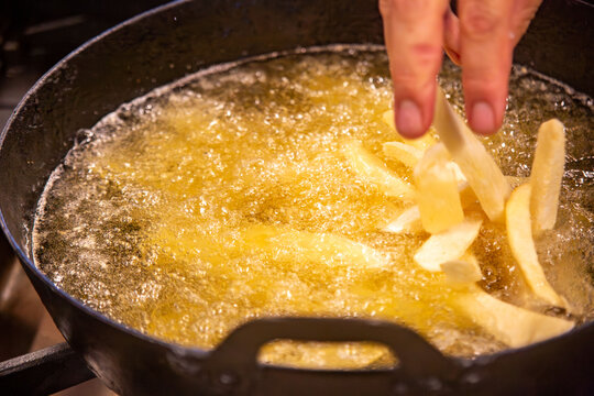 Fresh potato slices added to hot oil for deep frying