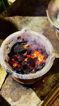 Golden egg omelet cooks in a metal pan over a traditional charcoal street stove.