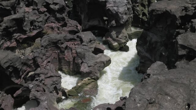 A high-angle shot of the naturally formed basalt rock potholes, locally known as Ranjan Khalge, carved over centuries by the Kukadi River in Nighoj, Ahmednagar district, Maharashtra, India.
