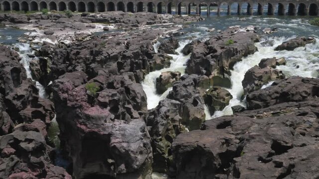 A high-angle shot of the naturally formed basalt rock potholes, locally known as Ranjan Khalge, carved over centuries by the Kukadi River in Nighoj, Ahmednagar district, Maharashtra, India.