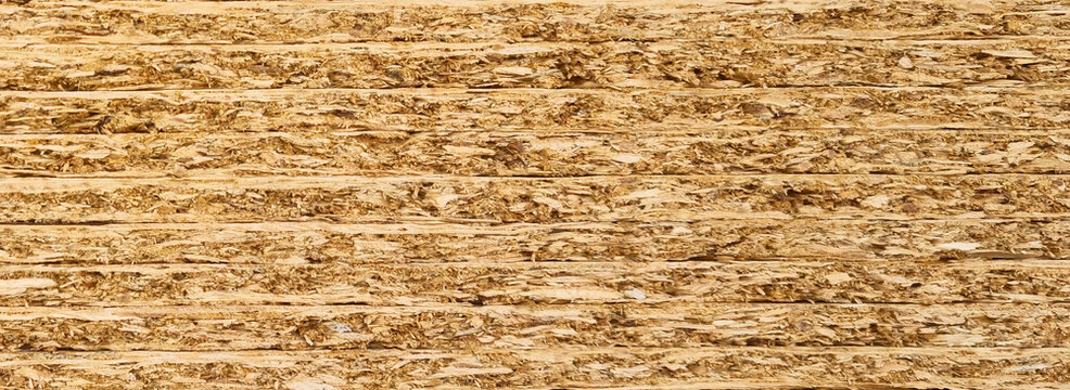 Oriented strand board OSB wood panel texture with compressed wood chips and horizontal pattern. Close up construction material background photography