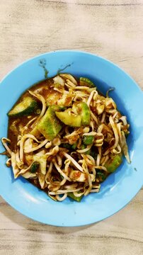 Savory stir-fried noodles with vegetables and bean sprouts are served on a blue plate.