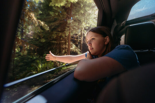 Young girl feels the wind from a car window