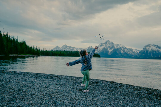 Young child throwing rocks into a mountain lake.
