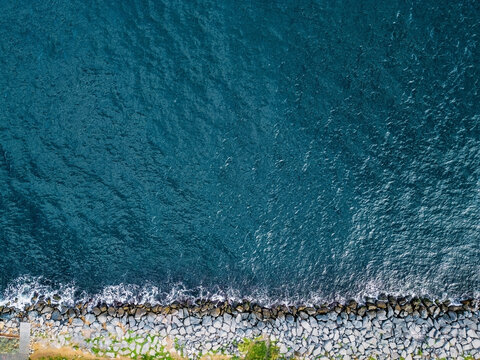 Aerial top down view of waves on rocky shore