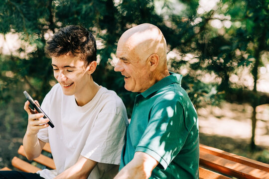 Grandson and grandfather laugh at a smartphone