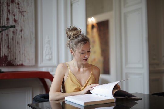 Elegant young woman reading a book at a table