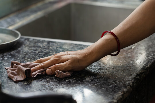 Indian female hand cleaning black granite kitchen countertop