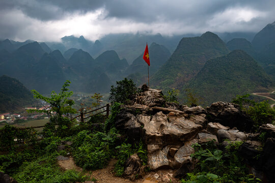 Scenic Mountain View featuring tall karsts, with a Vietnamese Flag and Lush Greenery in a Natural Landscape in Vietnam's Ha Giand Loop - horizontal