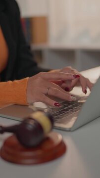 Female lawyer's hands typing on laptop with gavel