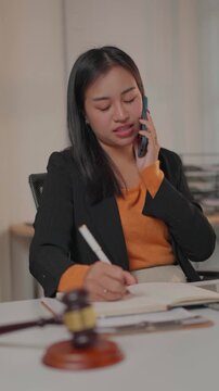 Professional asian lawyer talking on the phone and taking notes
