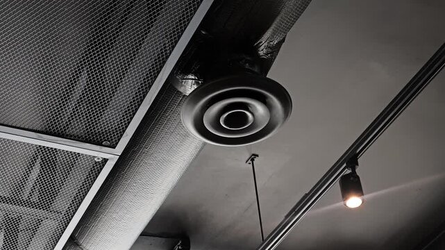 Round HVAC air diffuser on exposed ceiling ductwork system