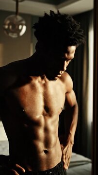 A muscular man stands in dramatic lighting within a room