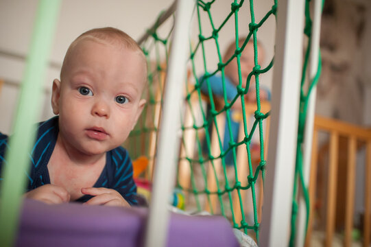 Twin boys lounge in a soft playpen, sharing moments of wonder and love in their cozy bedroom on a peaceful afternoon