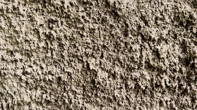 Close view of a coarse weathered concrete wall with rugged natural texture.