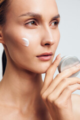 Woman applying cream for skincare on face closeup, beauty wellness selfcare concept, cotton pad and...