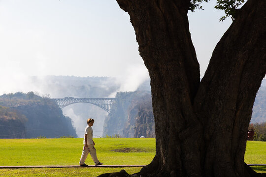 young boy walking past view of Victoria Falls and Victoria Falls Bridge from the Zimbabwe side, Zimbabwe, Africa