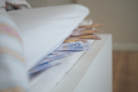 Money placed under a mattress in a bedroom setting