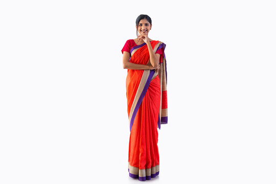Beautiful Indian woman in sari gesturing with hand on chin against white background