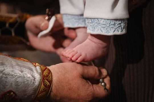 Baptism. Closeup of a priest's hands anointing a baby's foot with holy oil during a traditional Orthodox baptism or christening ceremony in a church.