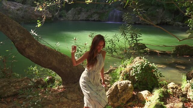 A woman stands beside a tranquil emerald green lagoon deep in the forest