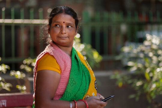 A house maid standing in the colony park using her mobile phone during her resting period 