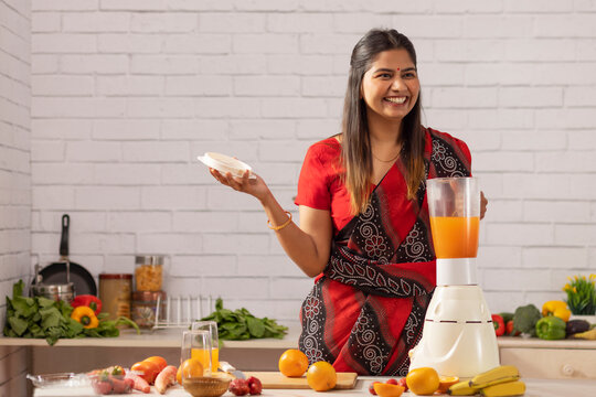 Smiling woman making orange juice in kitchen