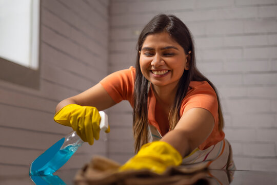 Woman cleaning the surface of table at home
