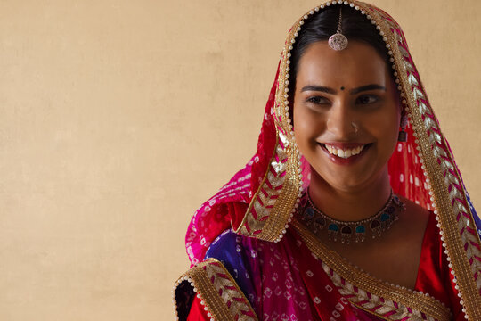 Close-up portrait of a cheerful Rajasthani young woman against plain background