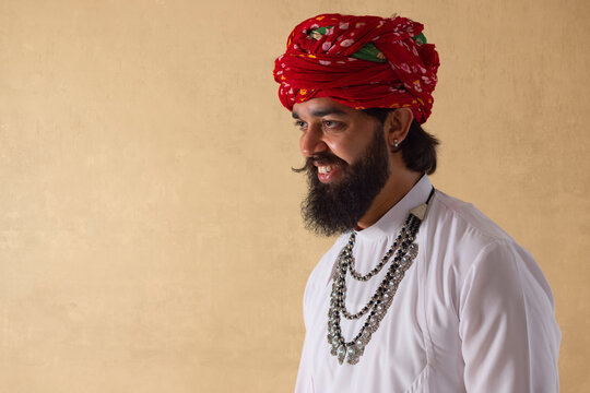Portrait of smiling Rajasthani young man standing against plain background