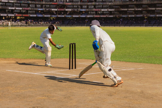 Batsman taking a run as the wicket keeper tries to run him out  during a cricket match