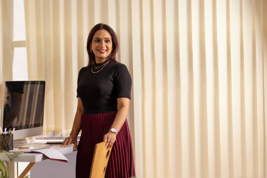 Portrait of a smiling female entrepreneur standing at her desk in office