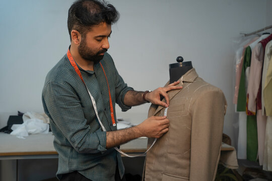 menswear designer working on a bespoke jacket in his studio 