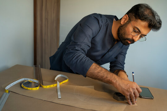 A male designer making patterns for a menswear collection in his studio 