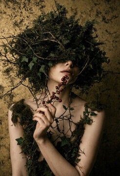 Artistic Portrait of a Forest Nymph Wearing Moss and Ivy Crown on Golden Background