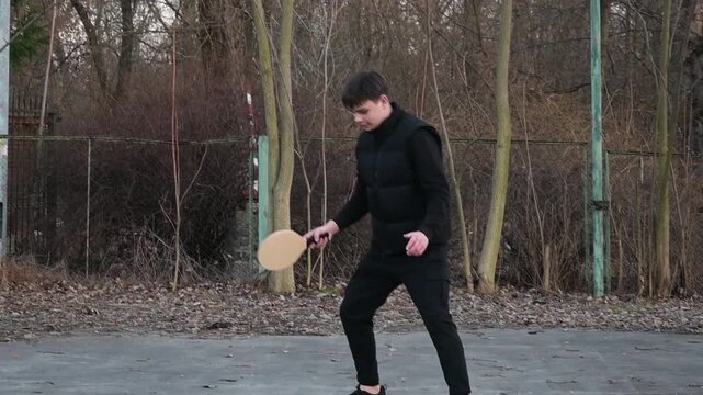 Active Teenager Playing Matkot Frescobol Game on Outdoor Court in Late Autumn