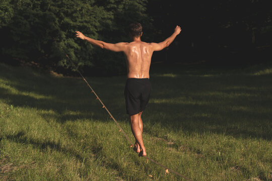 Young man balancing on tightrope over green grass, representing life balance, career stability, risk management, and overcoming challenges concept