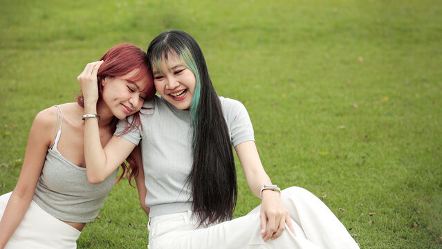 Happy LGBTQ+ couple relaxing together on green grass, celebrating love, equality, diversity, inclusion and emotional connection