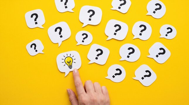 Hand pointing at a lightbulb icon among many question marks on yellow background with lightbulb question pointing