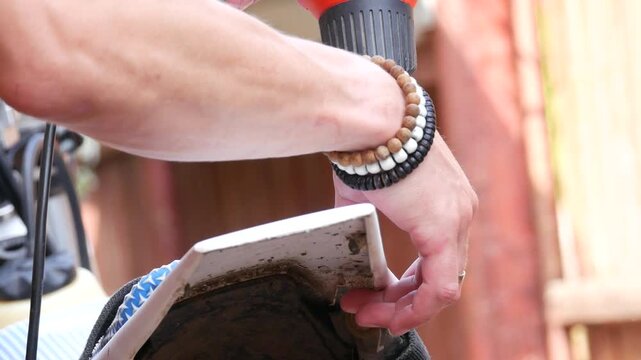 Man using heat gun to reshape plastic motorcycle fender. Mechanic repairing dirt bike part. Thermal tool heating plastic for repair, maintenance and customization.