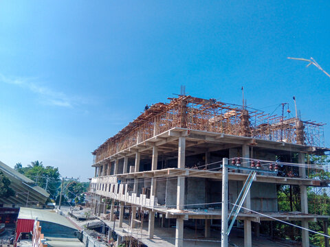 Unfinished multistory concrete building with steel reinforcement on a bright, sunny day. Suitable for construction, architecture, and real estate themes.