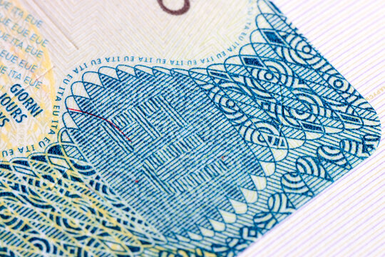 An extreme close-up view of an Italian Schengen visa shows complex microprinting, wavy guilloche patterns, and holographic elements designed to prevent counterfeiting and secure international travel.