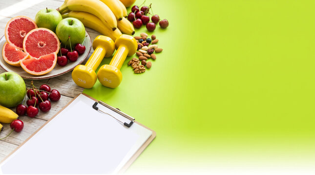 Fresh fruit and fitness journal on bright background. Healthy lifestyle concept with citrus, berries, and workout planning tools.