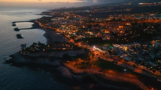 sunset at ocean shore and night illuminated city view, Tenerife, Canary island aerial drone view 4k