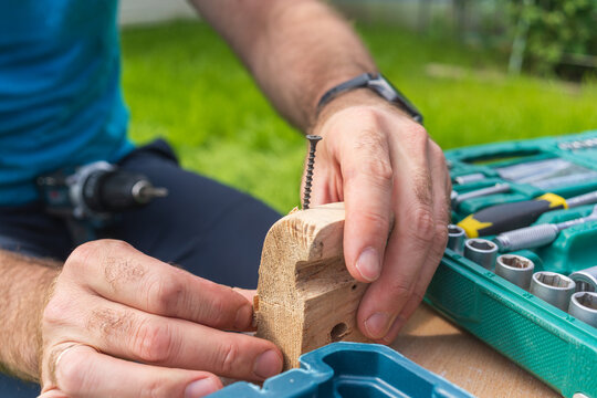 Hands assembling a wooden piece during DIY woodworking repair in backyard