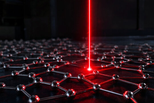 A red laser beam shining on a molecular structure in a dark laboratory setting