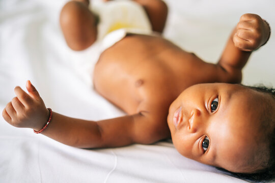 Cute shirtless newborn baby boy lying on bed at home