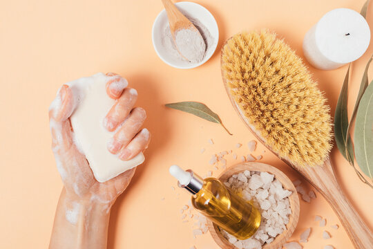 Woman holding wet soap bar near organic body care products