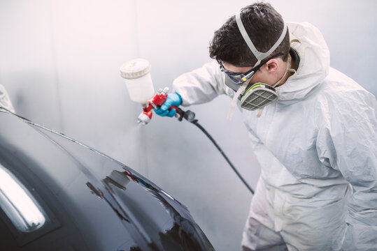 Auto painter painting a car inside a paint booth